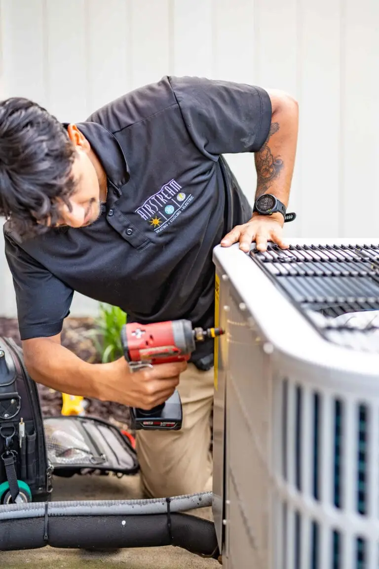 Airstream Services HVAC technician using a power tool to service an outdoor air conditioning unit during a repair visit in Middle Tennessee.