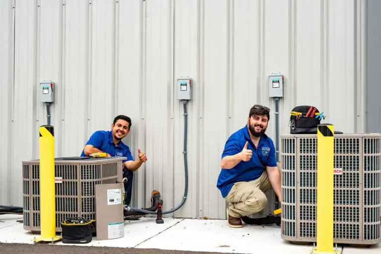 Airstream Services HVAC technicians giving a thumbs-up while installing new outdoor air conditioning units at a commercial property in Middle Tennessee.