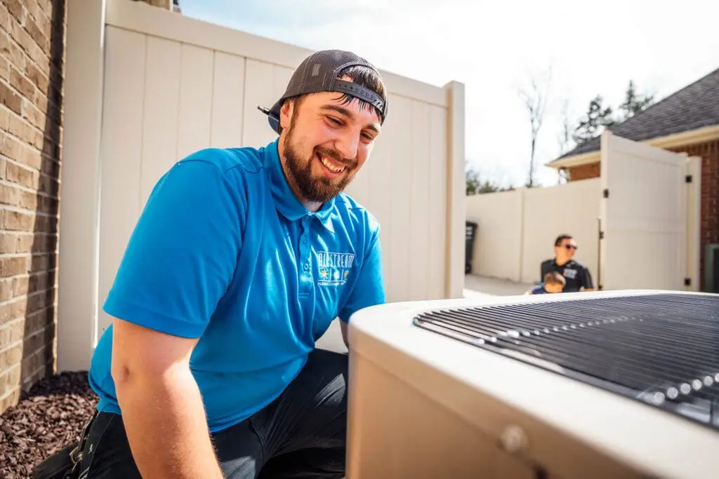 A smiling Airstream Services HVAC technician installing a new outdoor air conditioning unit at a Middle Tennessee home.
