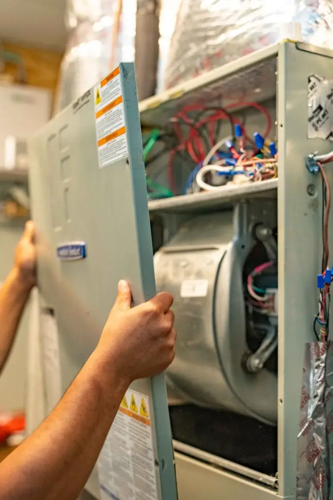 Technician opening an HVAC unit panel to inspect wiring and electrical components, a common source of electrical burning smells in homes.