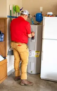 Airstream Services technician inspecting and adjusting a traditional tank-style water heater in a residential Middle Tennessee garage.