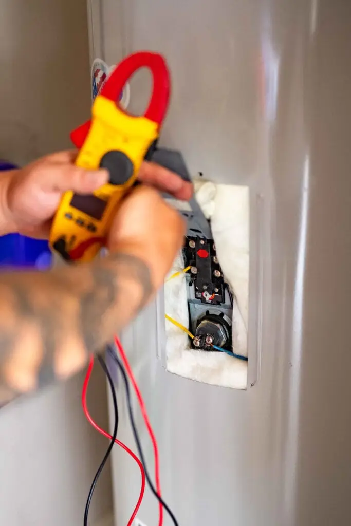 Airstream Services technician using a multimeter to test the electrical components of a water heater.