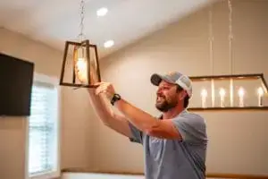 A licensed electrician installing a light fixture in a residential home in Murfreesboro, TN.