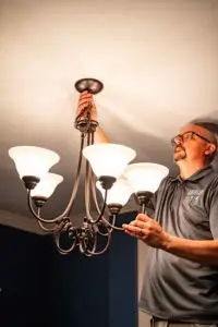 Electrician tightening a light fixture to fix flickering lights