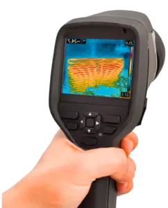 A hand holding a thermal imaging camera displaying a colorful heat signature, indicating electrical diagnostics.