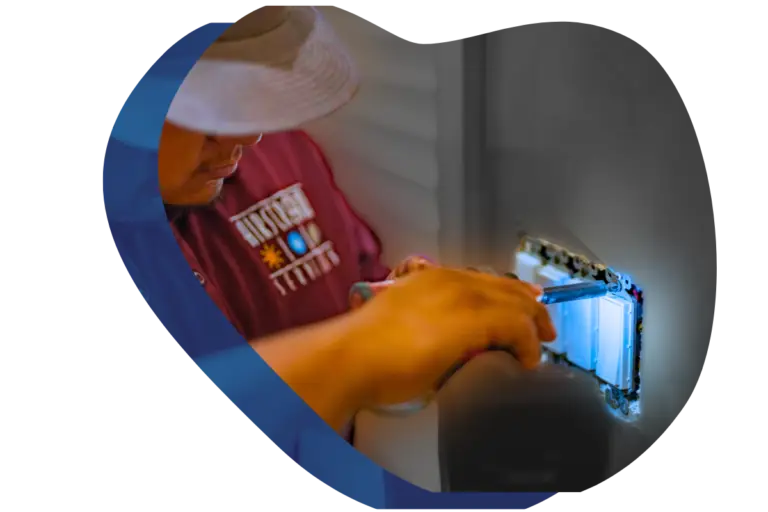 Electrician installing or inspecting an electrical outlet or switch box in a wall.