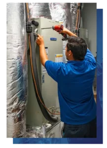 Airstream HVAC technician in a blue shirt using a power drill to service an indoor air handler unit.