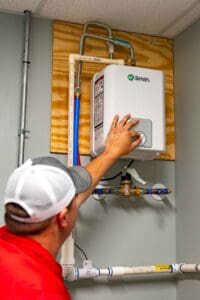 Technician adjusting a tankless water heater system mounted on a wall