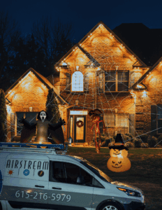 Mt. Juliet home decorated with fall and Halloween lights, inflatables, and Airstream Services van parked in front.